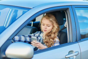 young woman using her smartphone while driving a car
